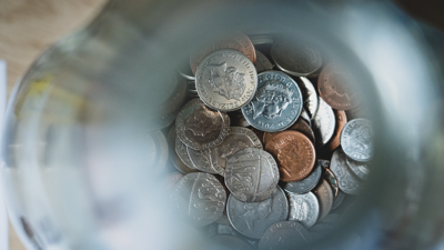 A close up, birds eye view of silver and copper coins in a glass jar.