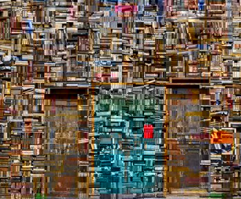 Huge piles of books surrounding an old blue door