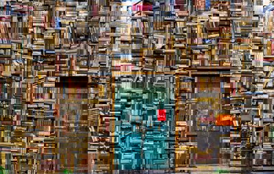 Huge piles of books surrounding an old blue door