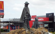 Statue of a farmer and dog in front of a McDonald's, symbolizing rural heritage contrasted with global fast-food branding in a modern setting.