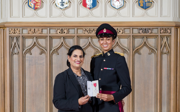 Preet Chandi posing with their mother, each holding a side of Preet's MBE.