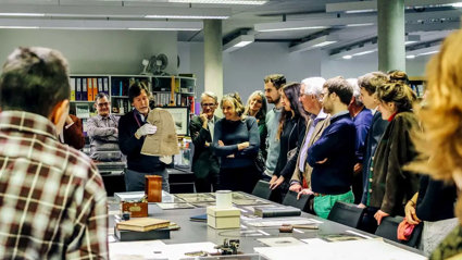 A group of people listening to a Society representative talk about an artefact from the collections.