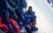 An expeditioner resting at a temporary shelter on the edge of a snow covered mountain.