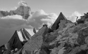 Tent perched on a rocky mountainside with Ama Dablam seen in distance.