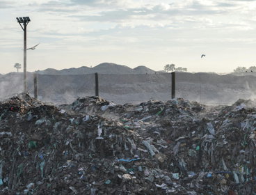 Landfill site with quarry in the background, with dust and birds in the air.
