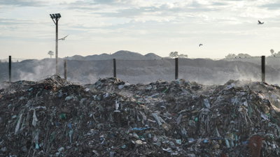 Landfill site with quarry in the background, with dust and birds in the air.