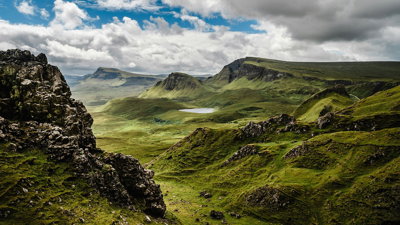 Green grass on a mountainouse landscape under a cloudy grey sky.