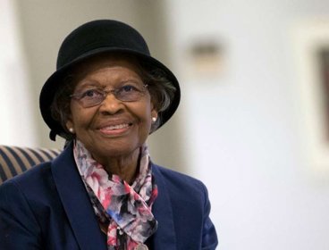 Gladys West wearing black hat and colourful scarf.