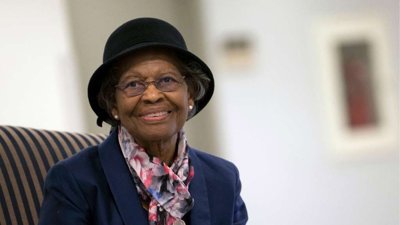 Gladys West wearing black hat and colourful scarf.