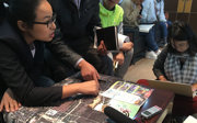 People gathered around a map in a planning meeting, pointing, taking notes, and using laptops.