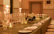 A close-up of glassware and tableware on a formal banquet table in a grand main hall. 