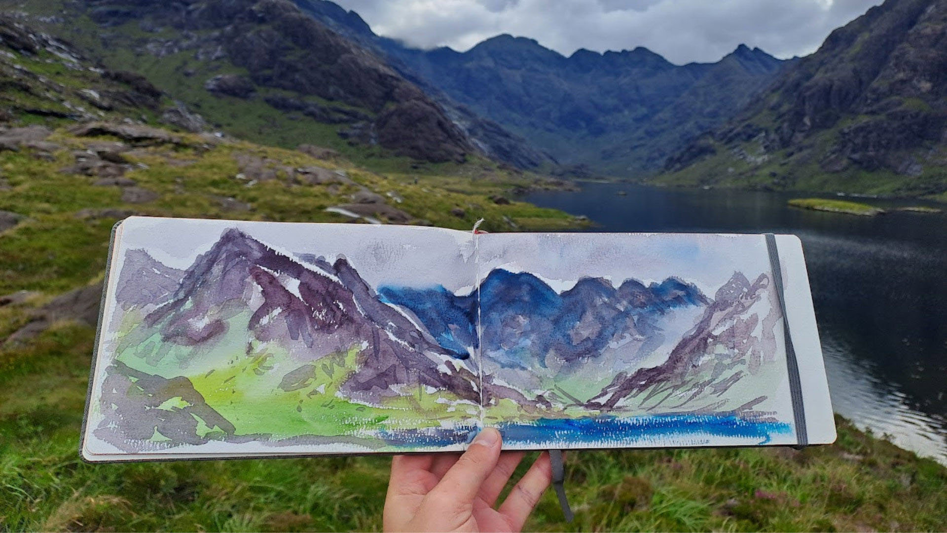 Watercolour painting of mountains, with mountains and lake in background.