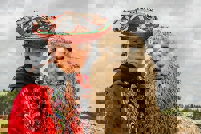 A woman with a sombrero standing with a llama