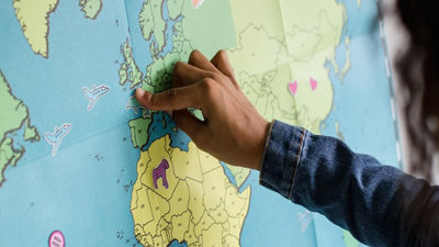 A child pointing to the UK on a map of the world.