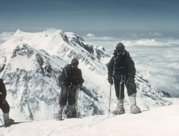 Three climbers ascenting snow-capped mountain.