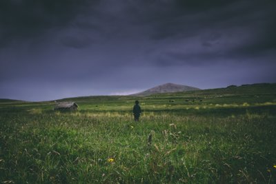 A boy in a field looking out over a stormy sky