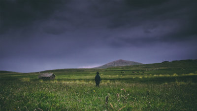 A child in a field looking out over a stormy sky.