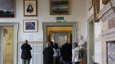 People on tour of historic building with pictures on the wall.