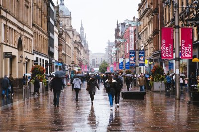 Poeple walk with either umbrellas or hoods up as it rains on Buchanan Street, Glasgow, United Kingdom