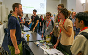 People at a conference networking with an exhibitor standing behind a table.