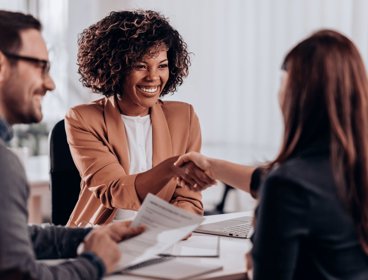 People shaking hands within corporate setting.