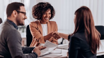 People shaking hands within corporate setting.