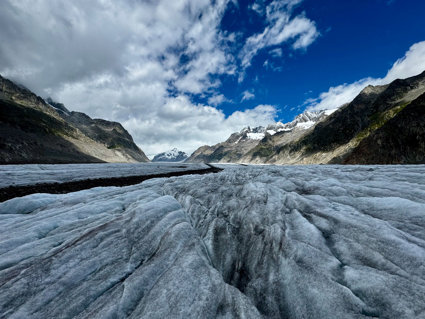 A blue grey glacier surrounded by mountains