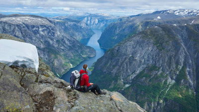 Person looking out across a mountain valley. A river meanders through the valley.