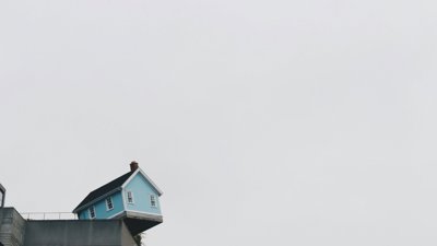 Blue house hanging on an edge.