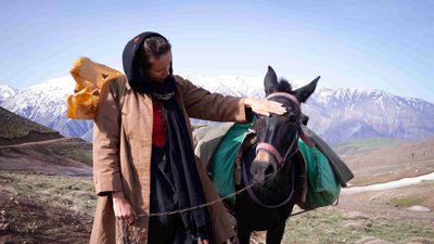 Elise stroking a donkey with mountains in the background