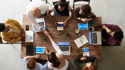 Aerial view of people working at laptops around a table.