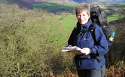 A woman in walking gear holding a map and trekking in nature.