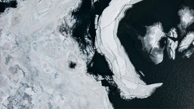 An aerial view of fragmented ice sheets floating on dark, cold waters.