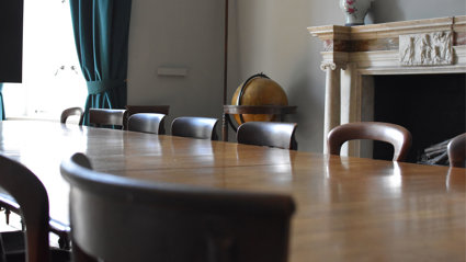 Close up of a large table and chairs in an old and stately meeting room.