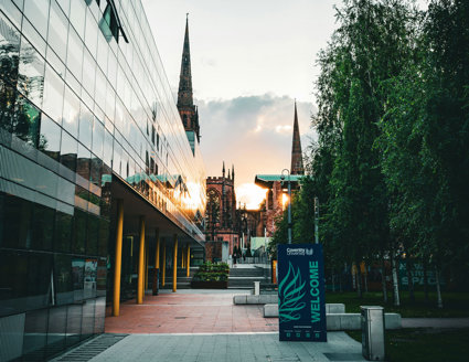 University campus with old and new buildings, with the sun setting in the background