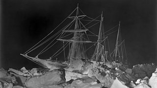 Old black and white photograph of Endurance stuck in ice at night.