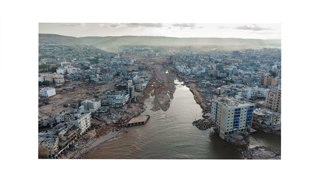 Aerial view of a river and a city with damaged buildings.