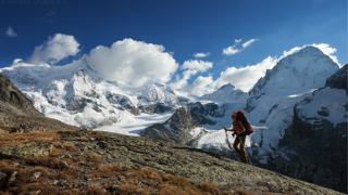Person hiking on mountain in snow-capped Swiss Alps.