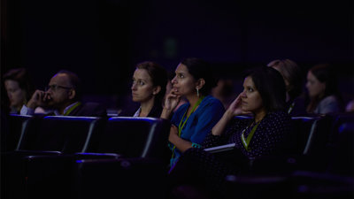 Group of people attending a conference in a lecture hall, listening attentively.