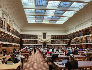 A large old looking library with high walls and a windowed ceiling