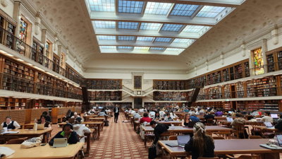 A large old looking library with high walls and a windowed ceiling