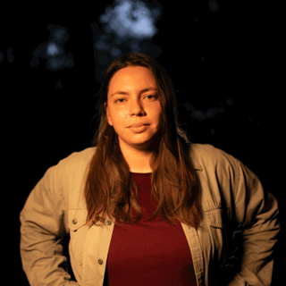 Person with long brown hair against black background.