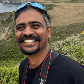 Person with moustache and beard smiling. 