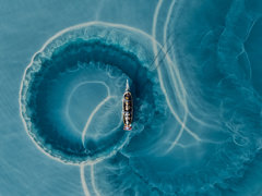 Boat making circular trails of silt in water.