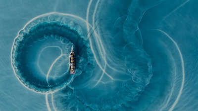 Boat making circular trails of silt in water.