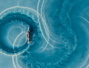 Boat making circular trails of silt in water