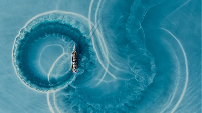 Boat making circular trails of silt in water