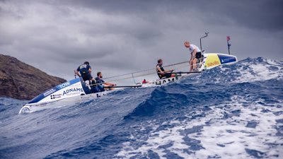 Row boat at sea amidst high waves and dark clouds.