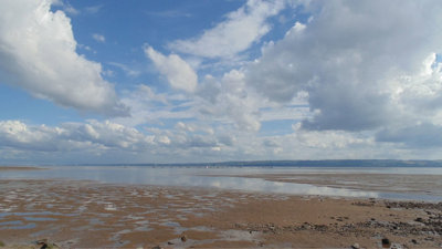 Estuary against a blue and cloudy sky.