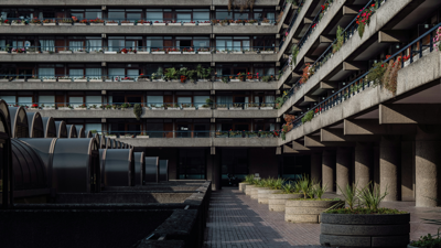 The grey concrete tower blocks of the Barbican estate. Plants and flowers scattered accross various balconies.
